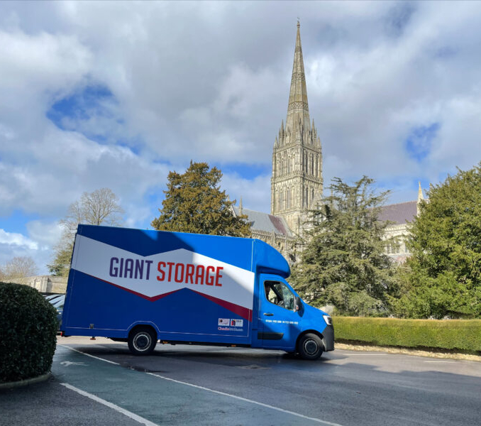 Blue van with Giant Storage written on side. Parked in front of cathedral